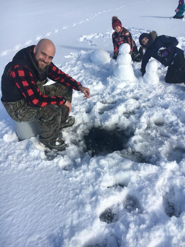 Ice fishing on a sunny winter day with kids and snowmen