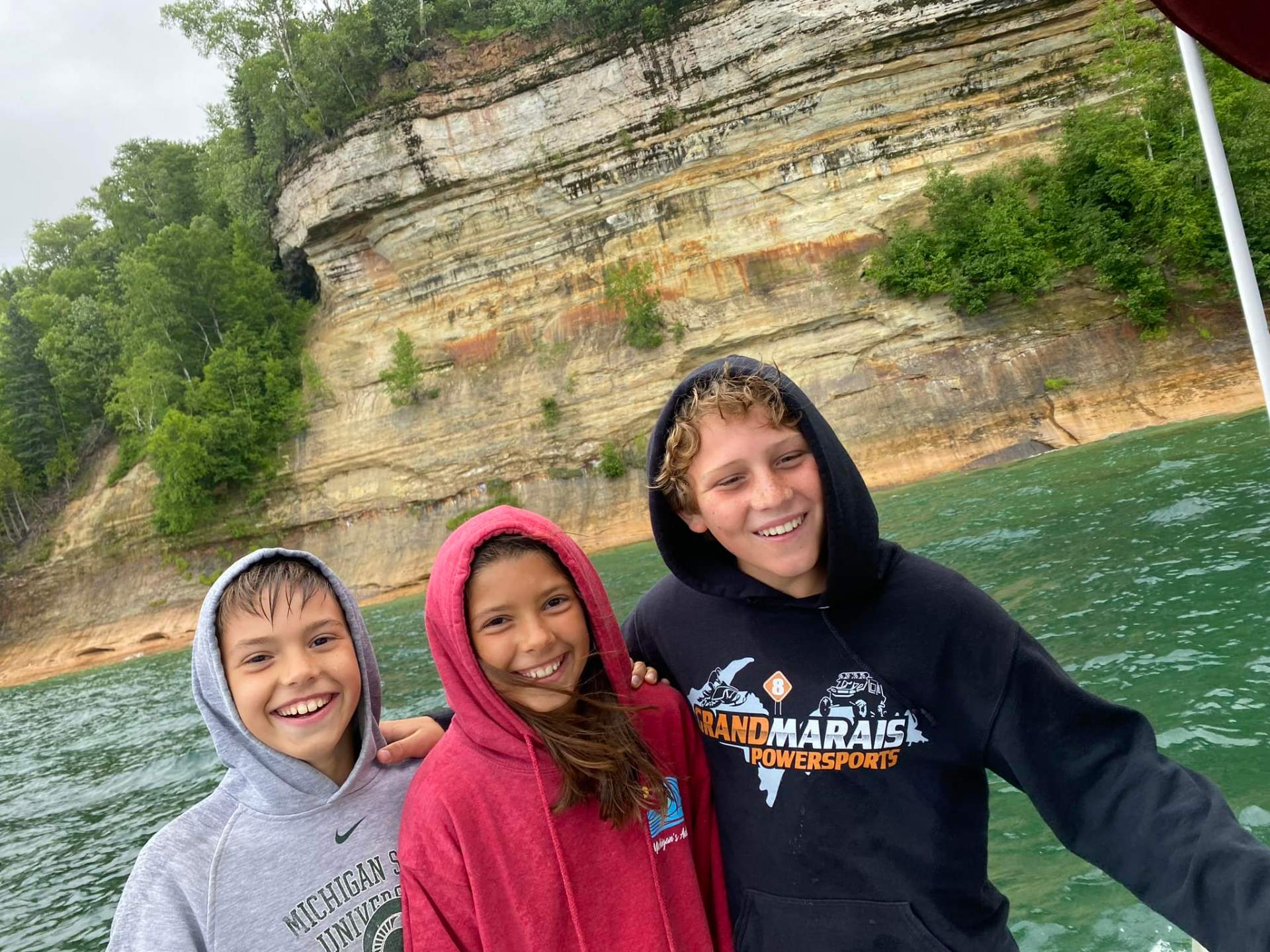 Kids smiling in front of the Pictured Rocks cliffs