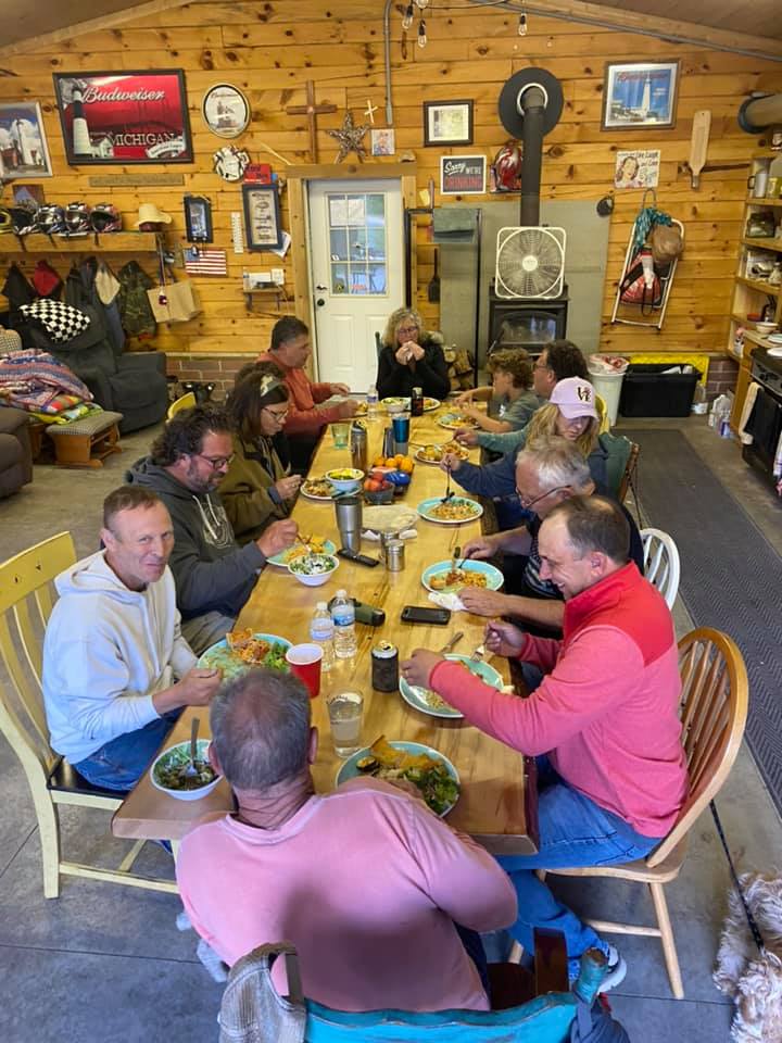 Family and friends sharing a meal at a long table in the cabin