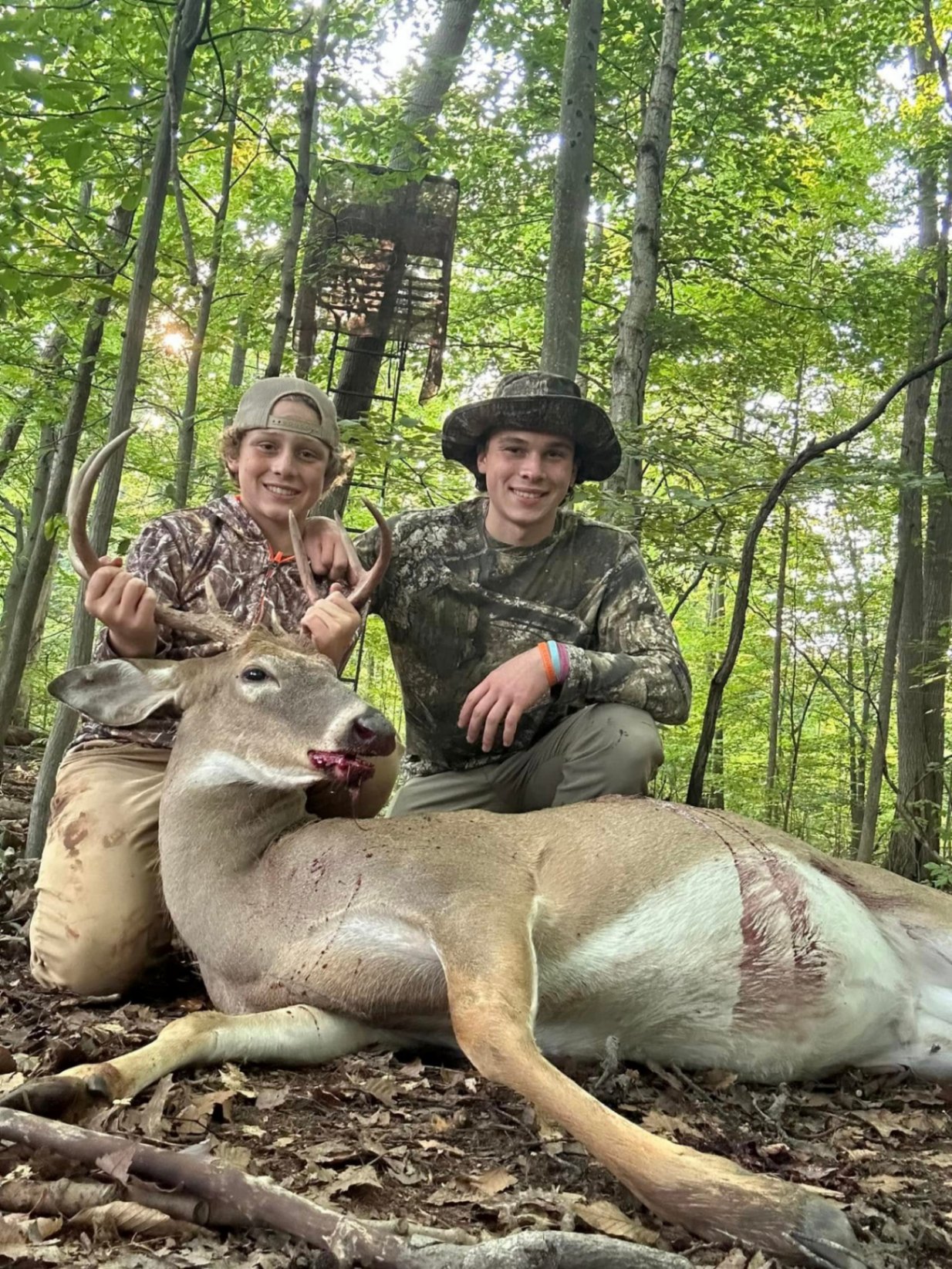 Two young hunters with a whitetail buck in the woods